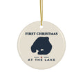 Round ceramic ornament with gold hanging string, navy lake silhouette and “First Christmas at the Lake” lettering on an ivory background.