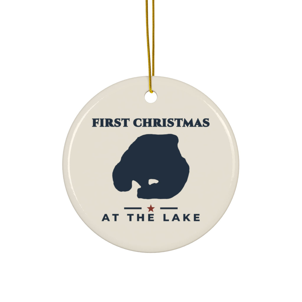 Round ceramic ornament with gold hanging string, navy lake silhouette and “First Christmas at the Lake” lettering on an ivory background.